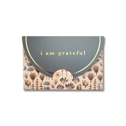 The Sweetness Floral 6 Pk Gift Card Envelopes by Maylay Co. are crafted from matte finish paper and showcase a green flap with the phrase "I am grateful." The bottom of each envelope is adorned with a floral pattern in muted shades of pink, brown, and green, enhanced by a subtle gold foil design for added elegance. These envelopes make an ideal choice for gift card holders.