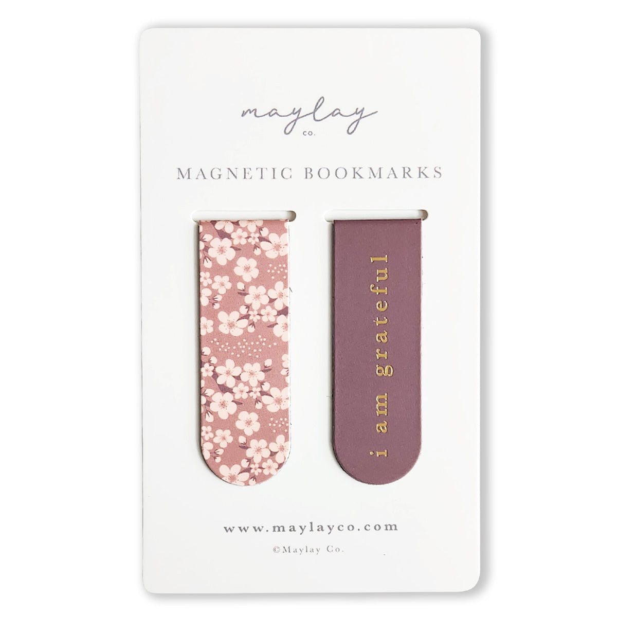 The Cherry Blossoms Floral Magnetic Bookmarks by Maylay Co. are thoughtful gifts featuring two distinct designs on a card. The left bookmark displays a lovely pink floral pattern, while the right one is a solid purple with "I am grateful" elegantly printed in gold. Enhance your reading experience with these charming accessories.