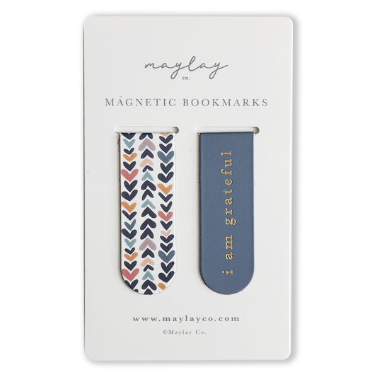 The Heartwood Magnetic Bookmarks (Set of 2) by Maylay Co. make delightful and thoughtful gifts. One bookmark is adorned with colorful hearts against a white background, while the other showcases a blue design with "i am grateful" in gold. The packaging proudly displays the brand name, Maylay Co., making these bookmarks ideal companions for enhancing your reading adventures.