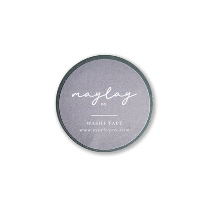 The "I Am Grateful Washi Tape - Sage Green" by Maylay Co. features a minimalist and sleek design, ideal for journaling or scrapbooking. It is a circular washi tape with a gray label where “maylay co.” is elegantly written in white cursive, along with “WASHI TAPE” and the website www.maylayco.com in smaller print.