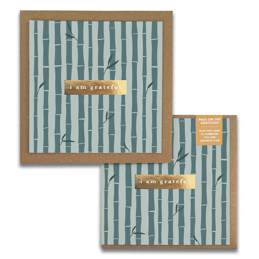 Two **Bamboo Gratitude Greeting Cards** by **Maylay Co.** feature elegant bamboo patterns and a gold foil section with the message "I am grateful." These cards, along with their brown envelopes, are perfect for expressing thanks. A small label on the top card inspires recipients to pass on gratitude.