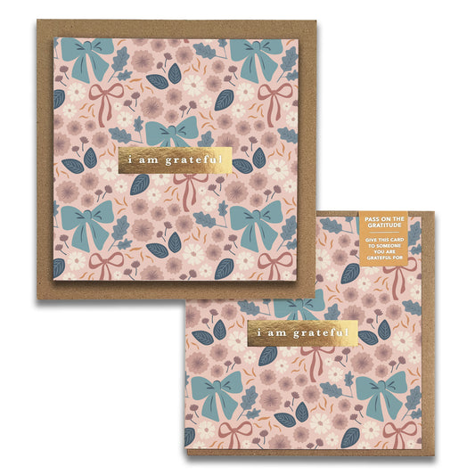 Two elegant Maylay Co. Bows Floral Gratitude Greeting Cards feature pink and blue floral patterns with bows. A gold label in the center reads "I am grateful." These thank you cards are beautifully displayed on brown envelopes.