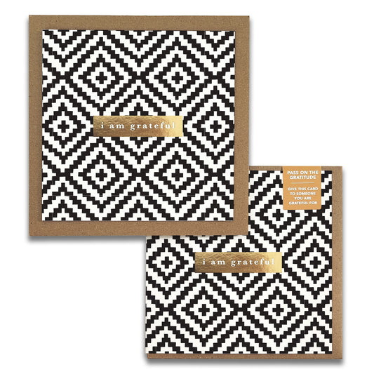 The Diamond Monochrome Gratitude Greeting Cards by Maylay Co. consist of two stylish cards adorned with a geometric black and white diamond pattern. Each card features a gold label with the words "I am grateful." These cards are elegantly packaged with a gold sticker, making them an ideal choice for expressing appreciation in a thoughtful way.