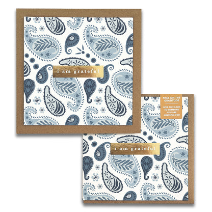 The Embroidery Gratitude Greeting Card by Maylay Co. features a blue and gray paisley design with the words "I am grateful" elegantly displayed on a gold banner, making it a perfect way to express appreciation when paired with its matching envelope.