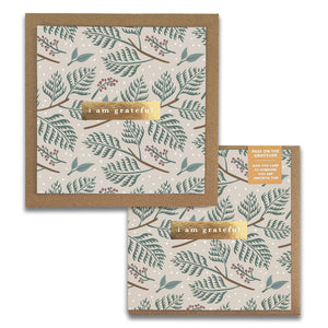 Maylay Co.'s Festive Holiday Gratitude Greeting Cards feature two square designs adorned with a nature-inspired pattern of leaves and berries set against a light gray background. Each card includes an elegant gold banner with the message "I am grateful." With one card being slightly larger, these cards are perfect for expressing your gratitude on any occasion.