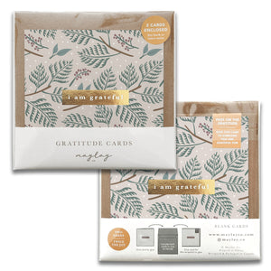 A set of two Festive Holiday Gratitude Greeting Cards by Maylay Co., adorned with a botanical pattern featuring green leaves and the phrase "I am grateful" on the front. These elegant greeting cards are blank inside, making them perfect for expressing sincere thanks and sharing gratitude.