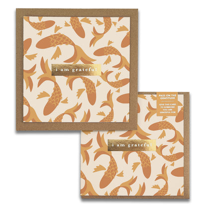 Introducing the Fish Gratitude Greeting Cards by Maylay Co. These cards feature an elegant orange koi fish pattern on a cream background, bordered in brown. The gold label boldly states "I am grateful." A matching smaller Thank You Card accompanies it, carrying the same design elements, making it an ideal choice for expressing heartfelt gratitude.