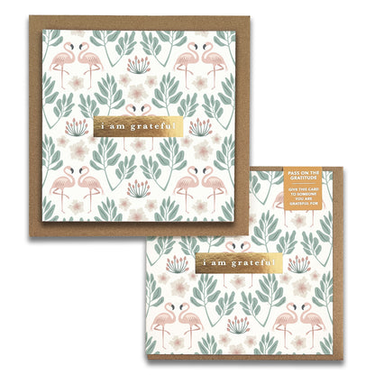 Introducing the Flamingos Gratitude Greeting Cards by Maylay Co.: a charming square card featuring a vibrant design of pink flamingos and green leaves. The centerpiece is a brown label with the inscription "Thank You." Accompanied by an envelope that mirrors the card's delightful motif, it's ideal for anyone in search of gratitude cards.