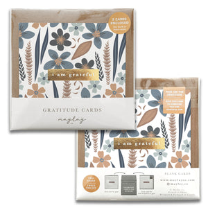 A set of Misty Bloom Gratitude Greeting Cards from Maylay Co. features a premium floral design with blue, brown, and beige flowers, accompanied by the text "I am grateful." The packaging prominently displays the inclusion of two cards.