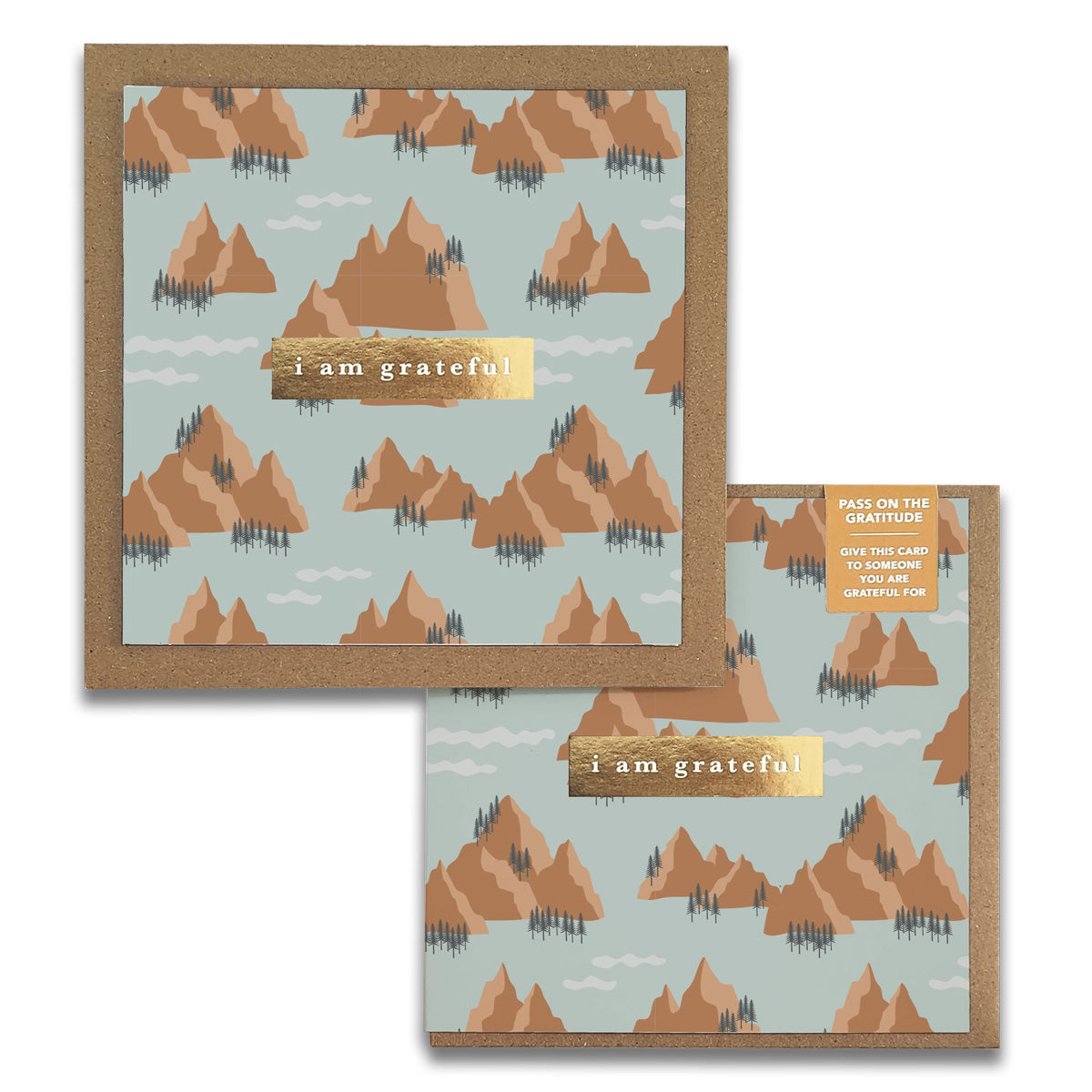 Maylay Co.'s Mountains Gratitude Greeting Cards showcase a printed design of brown mountains and evergreen trees set against a light blue backdrop. The elegant text "I am grateful" is beautifully highlighted in the center on a gold bar, making them ideal for expressing thanks with style.