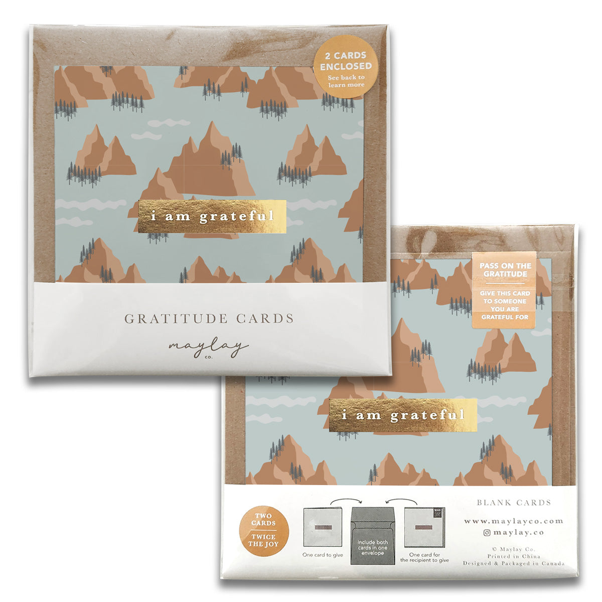 Two sets of Maylay Co.'s Mountains Gratitude Greeting Cards showcase a design with mountains and trees on a light blue background. Each set contains two elegant cards, ideal for expressing gratitude. The packaging is labeled 'i am grateful' alongside 'GRATITUDE CARDS.'