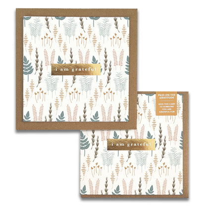 Nature Walk Gratitude Greeting Cards from Maylay Co. are square gratitude cards adorned with pastel floral illustrations and the text "I am grateful" on a golden strip. A label encourages you to share your appreciation by giving this thank you card to someone special.