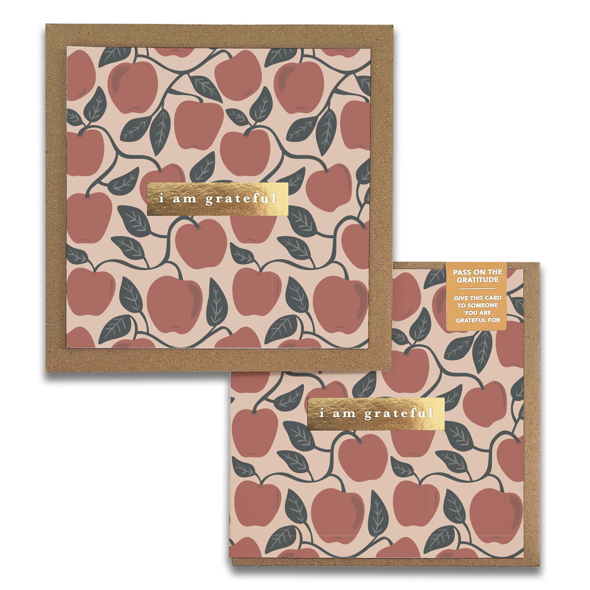 Introducing the Orchard Apples Gratitude Greeting Cards by Maylay Co., featuring a charming pattern of red apples and green leaves set against a beige backdrop. The front showcases a gold label with the heartfelt message "I am grateful." Accompanied by a matching brown envelope, this card is ideal for expressing your gratitude.