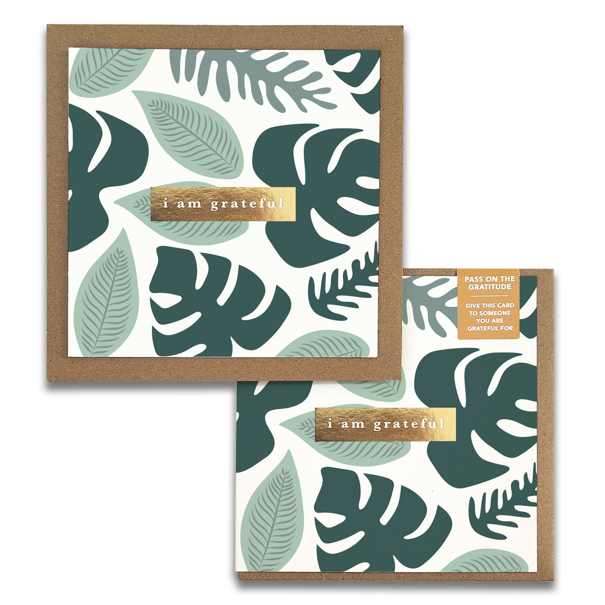 Maylay Co.'s Rainforest Gratitude Greeting Cards showcase two cards adorned with leafy designs in green hues, featuring "I am grateful" elegantly embossed in gold on a brown strip. These gratitude cards are artistically presented on a rustic brown craft-paper background.