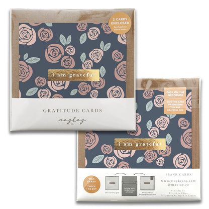 The "Roses Gratitude Greeting Cards" by Maylay Co. feature a floral design with pink roses set against a dark background. The packaging is labeled Gratitude-Inspired with the message I am grateful and includes two cards with blank interiors to encourage sharing gratitude.