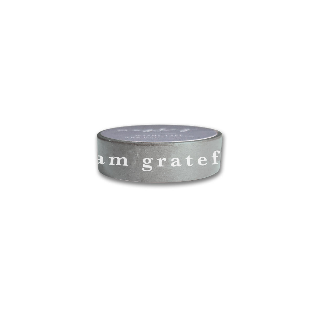 The Sage Green "I Am Grateful" Washi Tape by Maylay Co. is an ideal choice for scrapbooking. It has a smooth, slightly reflective surface and features the phrase "I am grateful" in white letters against its circular body, set against a plain white background.