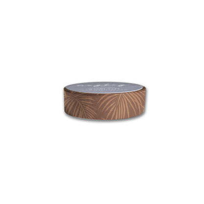 Introducing the Palms Washi Tape by Maylay Co.—a delightful roll of decorative tape, ideal for journaling or scrapbooking. It showcases a brown background adorned with subtle palm leaf patterns, lending an artistic touch to your creative projects. The cylindrical form is slightly blurred at the top, enhancing its visual appeal.