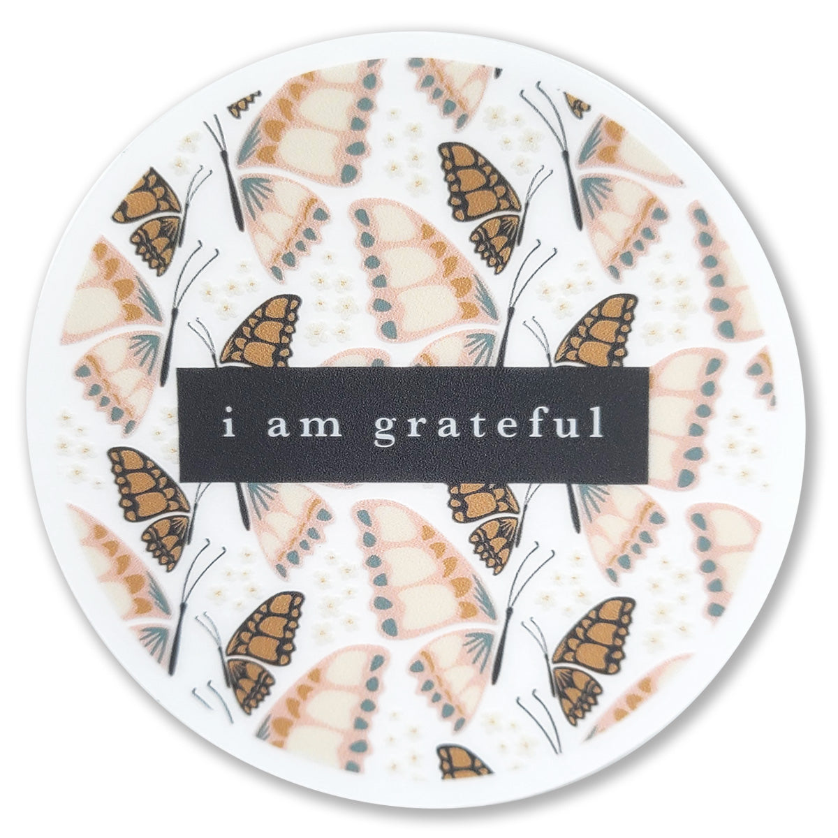 The Butterfly 3" Clear Gratitude Sticker from Maylay Co. is a round transparent vinyl sticker featuring a pattern of butterflies in earthy tones and the phrase "I am grateful" at its center, set against a black background. #PASSONTHEGRATITUDE