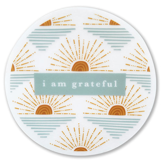 This round design, part of Maylay Co.'s Gratitude Collection, features "I am grateful" at its center and is adorned with a stunning pattern of orange and yellow sunbursts on a white background. It's ideal as the Sunrise 3" Clear Gratitude Sticker to #PASSONTHEGRATITUDE.